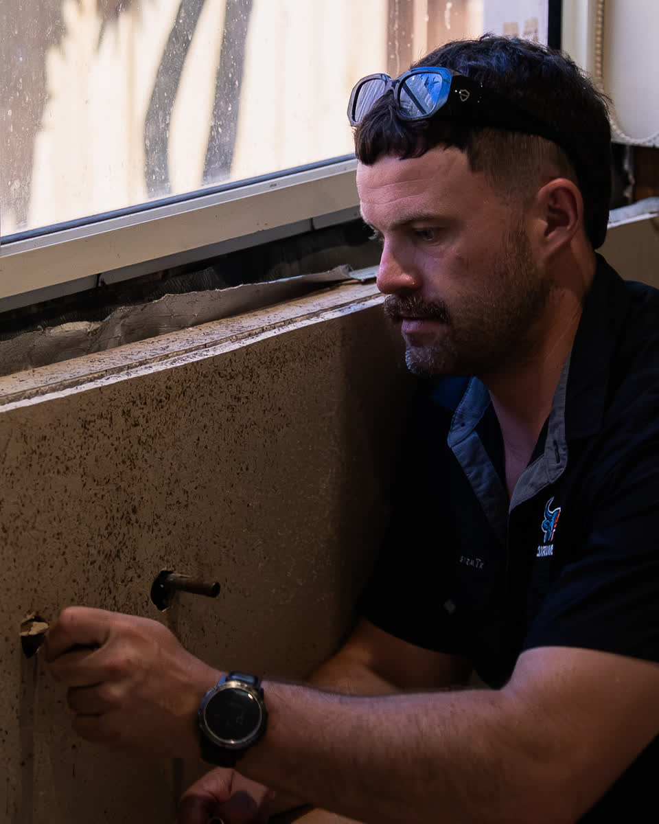 Joel working on a pipe in a wall