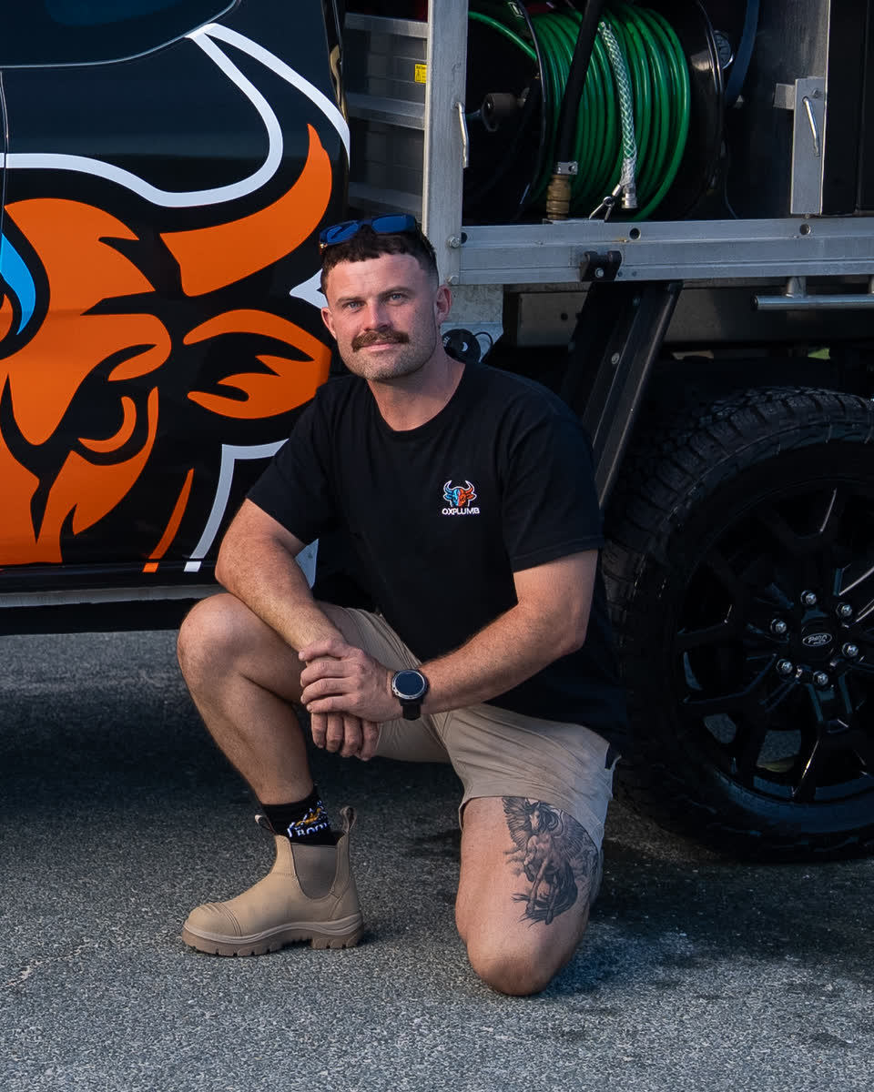 Joel kneeling beside the Oxplumb ute