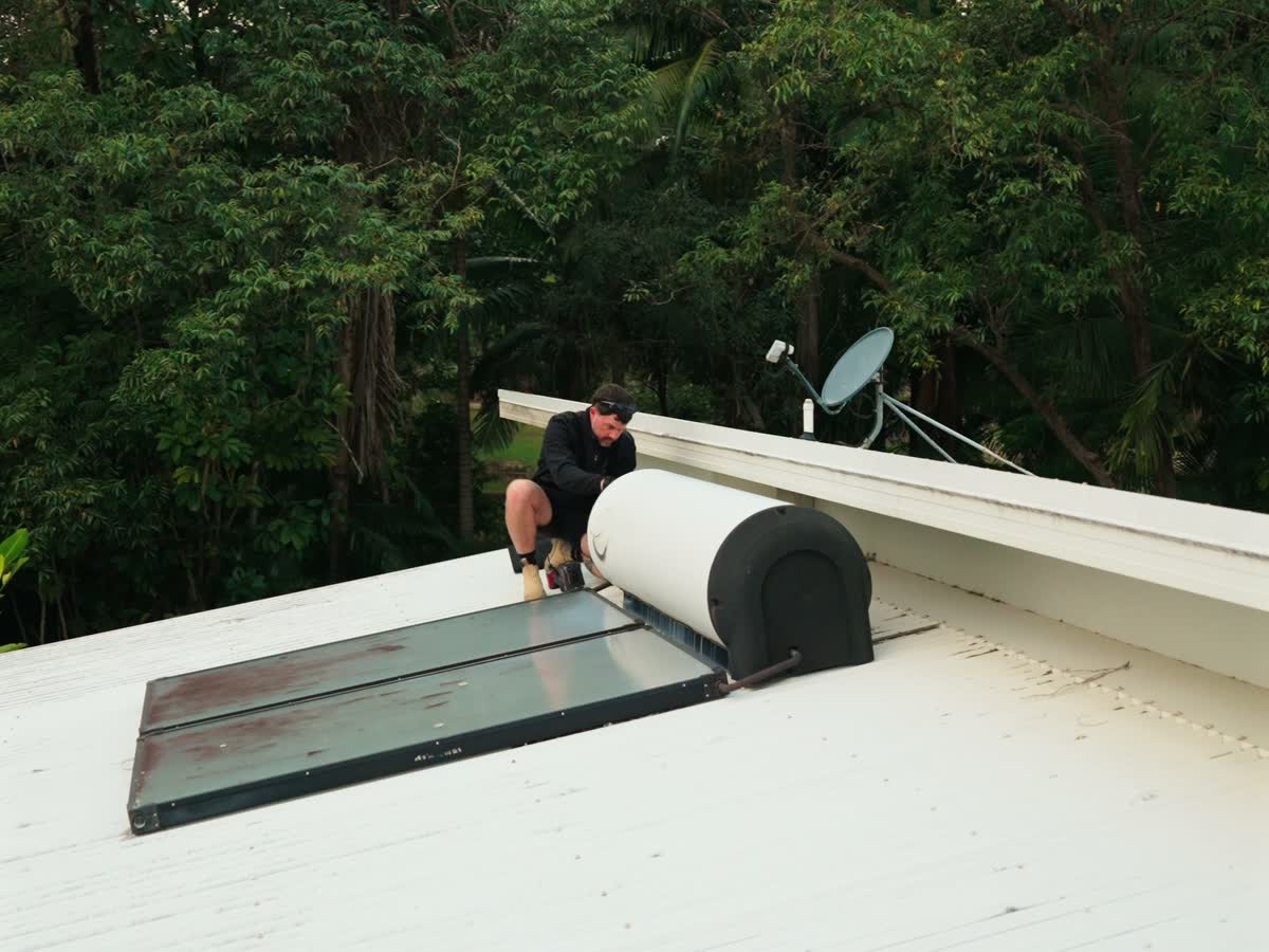 Joel on a roof beside a solar hot water system