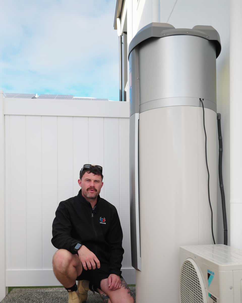 Joel crouching beside a hot water tank