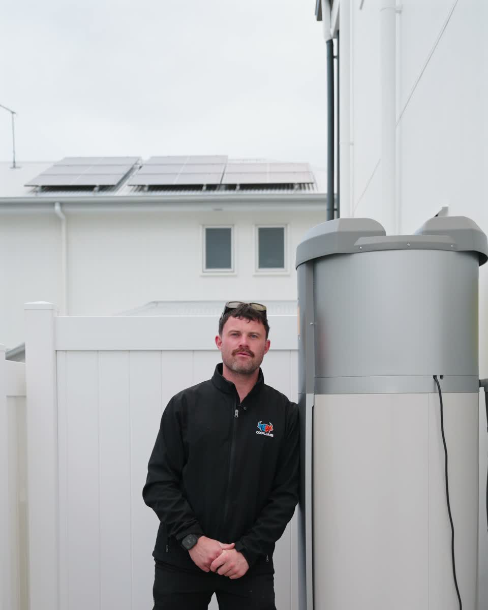 Joel beside a heat pump hot water system